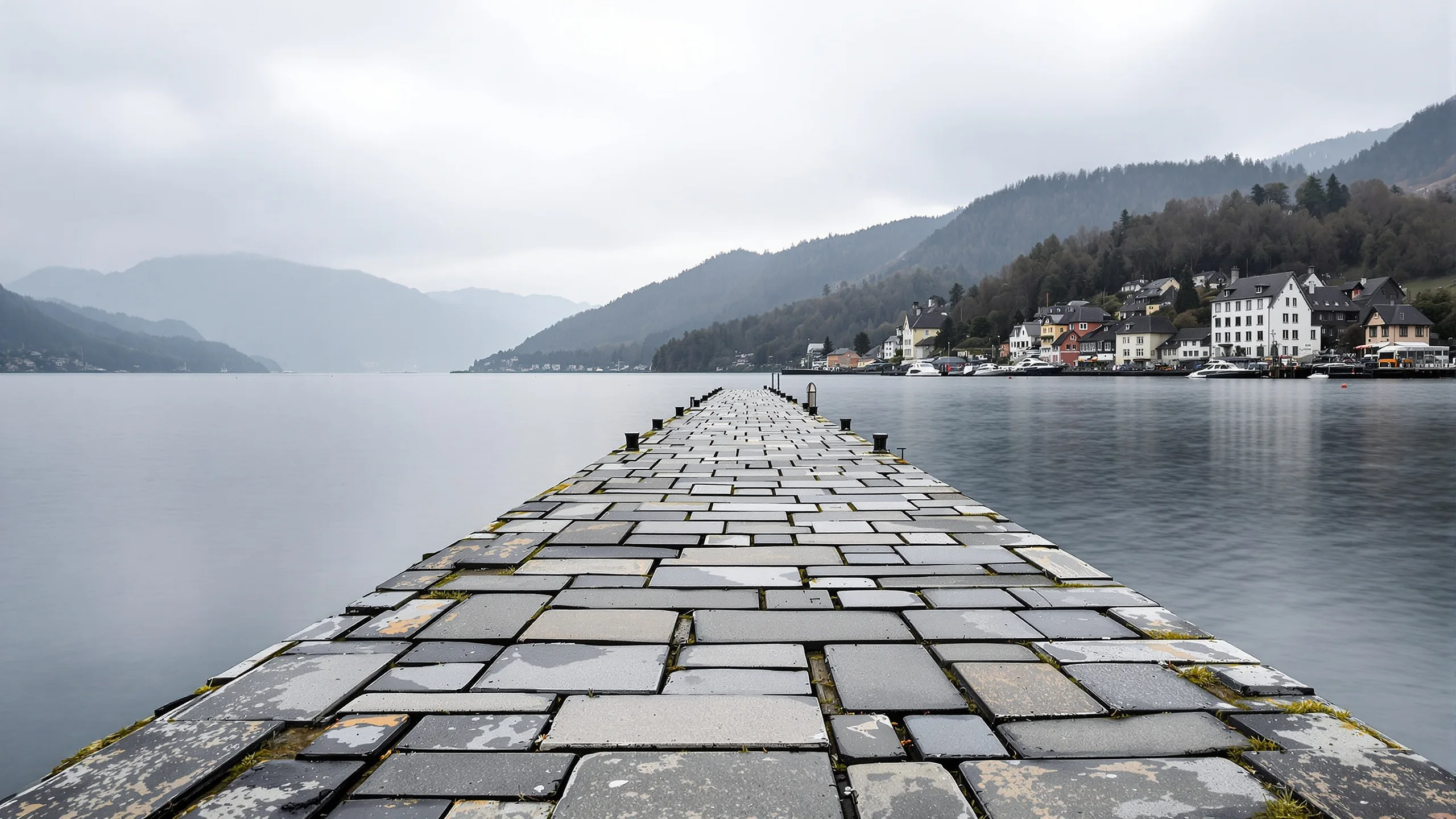 A weathered stone lakeside quay of a small Swiss town, worn flagstones and old iron mooring rings by calm water